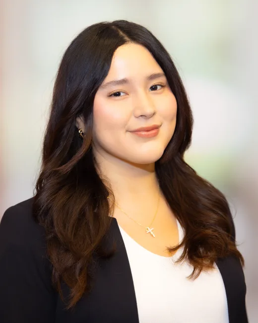 Professional headshot of a woman in a black blazer with studio lighting